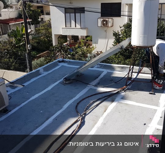 אדם מורח חומר איטום על גג שטוח